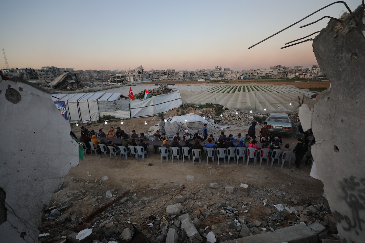 يتجمع فلسطينيون نازحون لتناول وجبة الإفطار وسط أنقاض المباني المدمرة في مدينة غزة، خلال شهر رمضان المبارك، في 25 فبراير/شباط 2026. صورة: عمر أشتوي