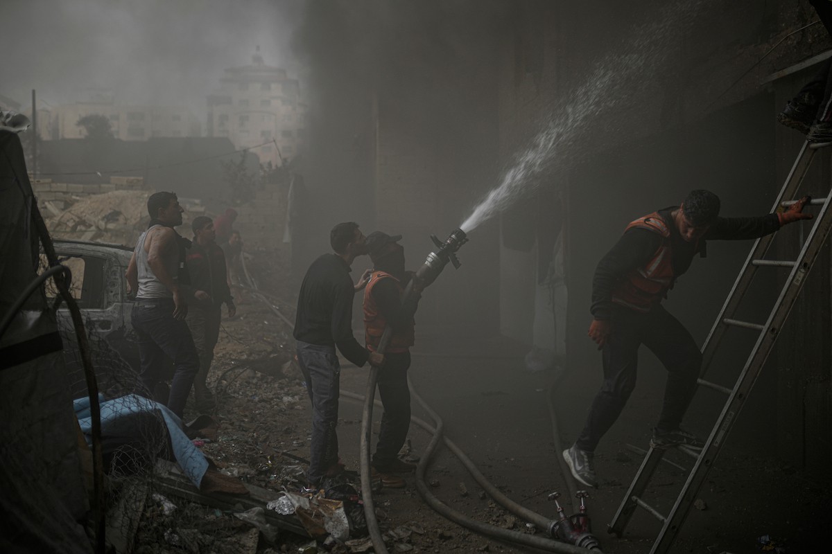 طواقم الدفاع المدني ومتطوعون من المواطنين أثناء محاولة إخماد حريق اندلع في مستودع تابع لمنظمة إغاثة في حي الرمال، غرب مدينة غزة، في 13 فبراير/شباط 2026. صورة: عمر أشتوي