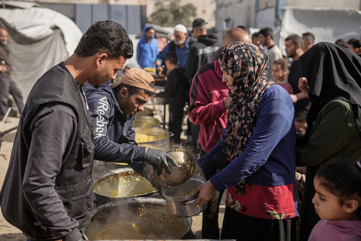 فلسطينيون بينهم أطفال ونساء يتلقون مساعدات غذائية وزعتها منظمات خيرية في أحد مراكز الإيواء بمدينة غزة، وسط أزمة غذائية مستمرة ناجمة عن محدودية المساعدات الإنسانية والظروف الإنسانية المتردية التي يواجهها النازحون، ١٢ فبراير/شباط ٢٠٢٦. تصوير: عمر أشتوي