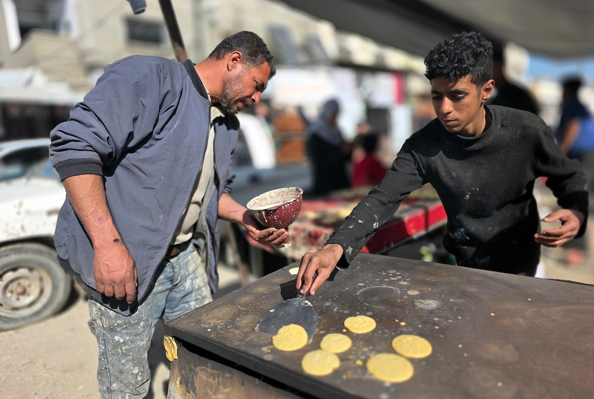 بائعٌ يُعدّ حلوى القطايف الشهيرة بالطرق التقليدية احتفالاً بشهر رمضان المبارك. ورغم الظروف المعيشية الصعبة، يواصل السكان شراء هذه الحلوى التقليدية. خان يونس، جنوب قطاع غزة، ٢٢ فبراير ٢٠٢٦. تصوير: طارق محمد