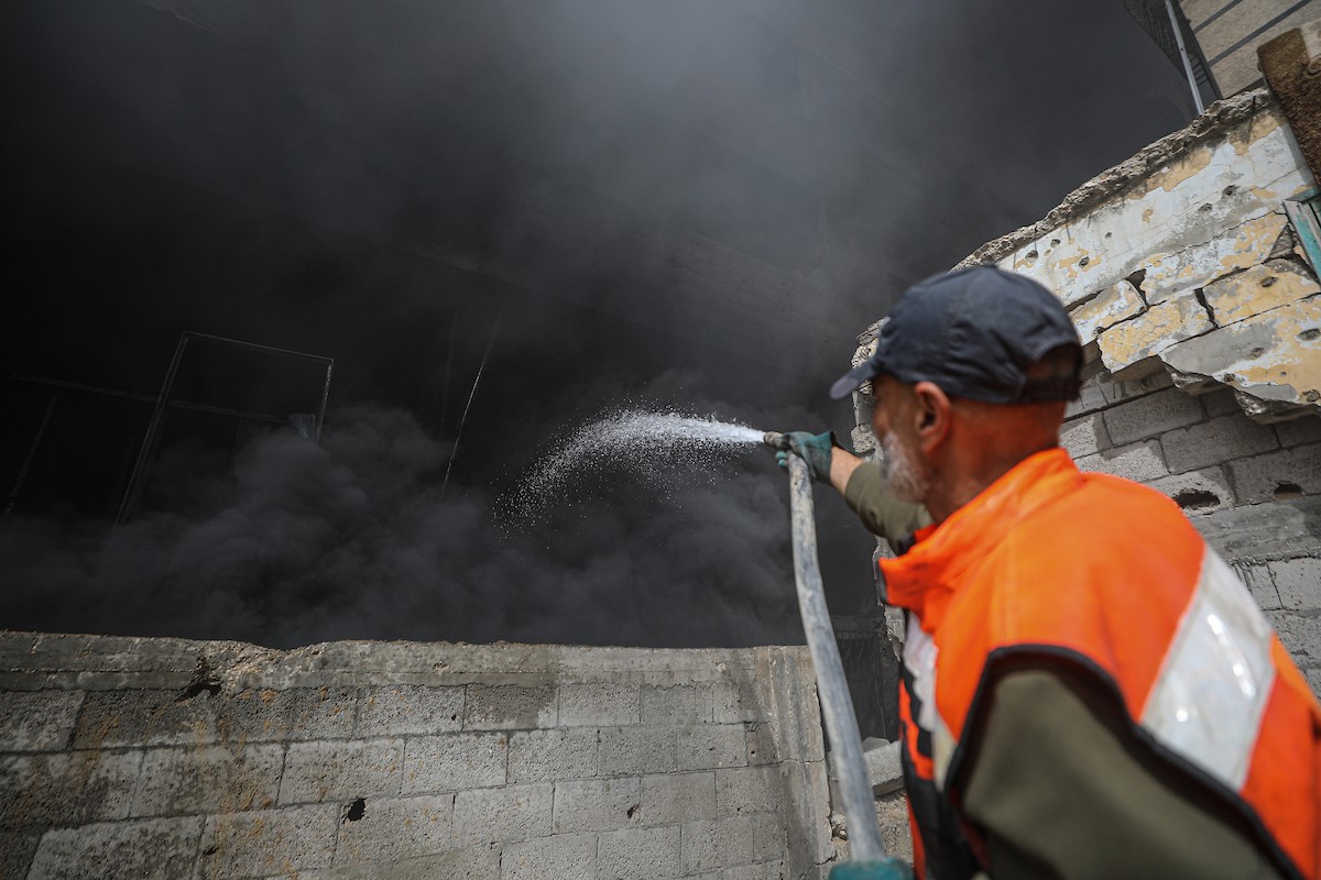 طواقم الدفاع المدني ومتطوعون من المواطنين أثناء محاولة إخماد حريق اندلع في مستودع تابع لمنظمة إغاثة في حي الرمال، غرب مدينة غزة، في 13 فبراير/شباط 2026. صورة: عمر أشتوي