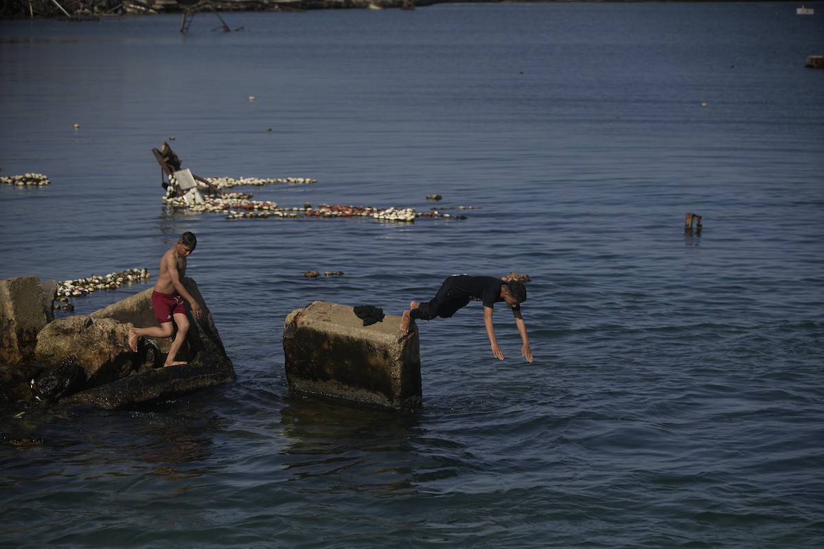 يسبح أطفال قرب ميناء غزة المدمر، في مشهد يعكس تمسكهم بلحظات الفرح رغم الدمار المحيط بهم. يُعدّ البحر في غزة المتنفس الوحيد لسكانها الذين يواجهون آثار الحرب والنزوح، والذين يعيشون في خيام تفتقر لأبسط مقومات الحياة، ١٢ فبراير ٢٠٢٦. تصوير: عمر أشتوي