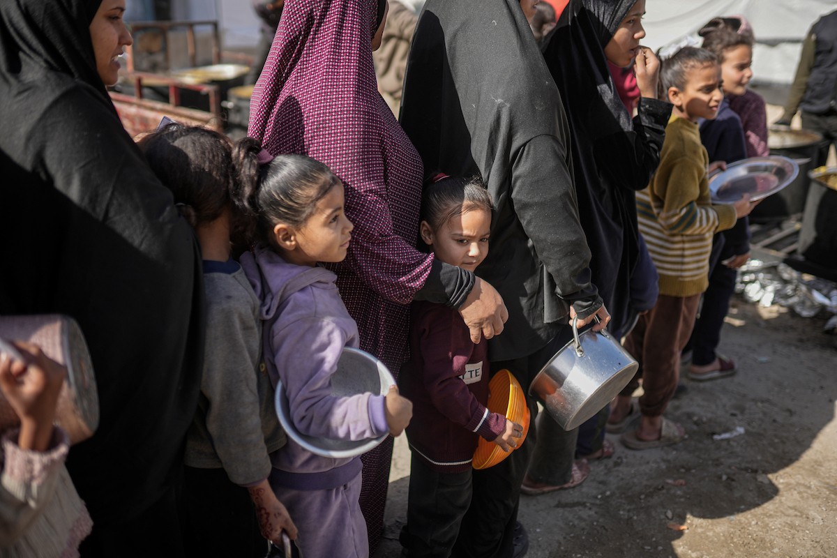 فلسطينيون بينهم أطفال ونساء يتلقون مساعدات غذائية وزعتها منظمات خيرية في أحد مراكز الإيواء بمدينة غزة، وسط أزمة غذائية مستمرة ناجمة عن محدودية المساعدات الإنسانية والظروف الإنسانية المتردية التي يواجهها النازحون، ١٢ فبراير/شباط ٢٠٢٦. تصوير: عمر أشتوي