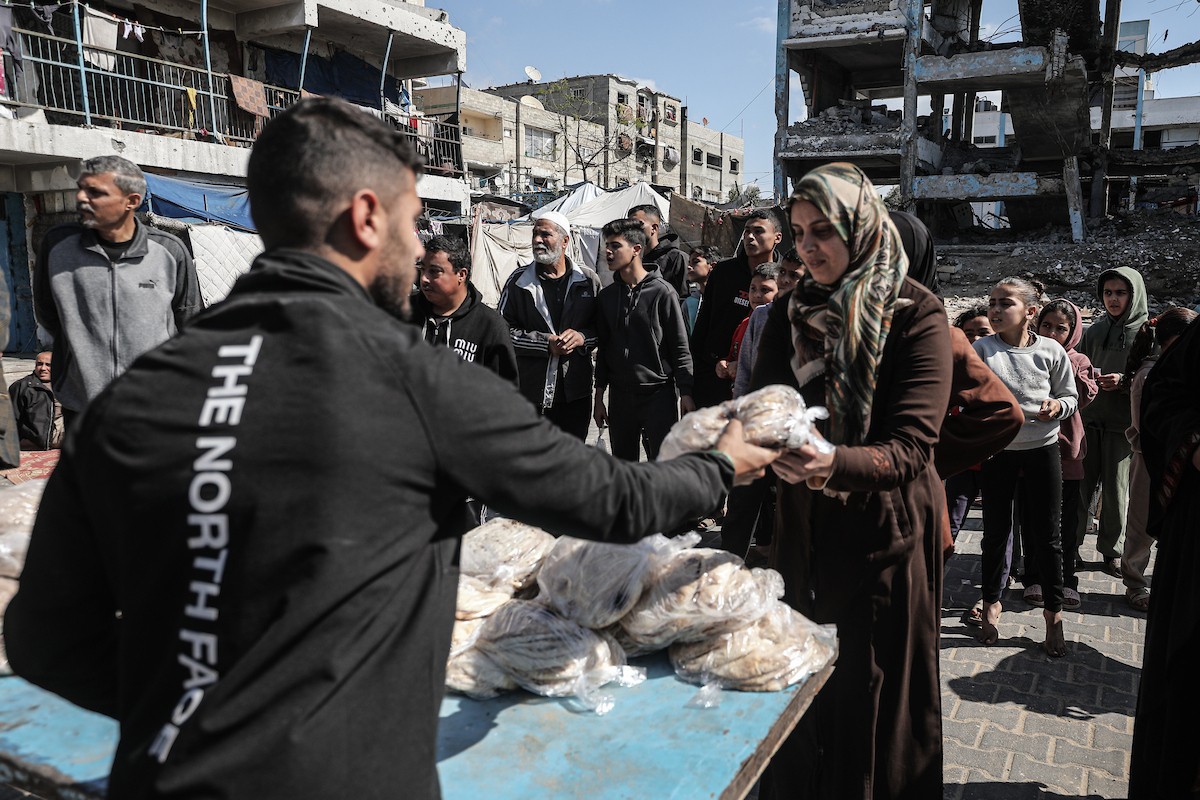 نساء فلسطينيات، زوجات شهداء الحرب، يُجهّزن الخبز لتوزيعه على العائلات النازحة والمحتاجة في مخيم البريج للاجئين وسط قطاع غزة خلال شهر رمضان، في مشهد يُجسّد روح التضامن والصمود في ظلّ الظروف الإنسانية الصعبة، فبراير/شباط 2026. تصوير: معز صالحي