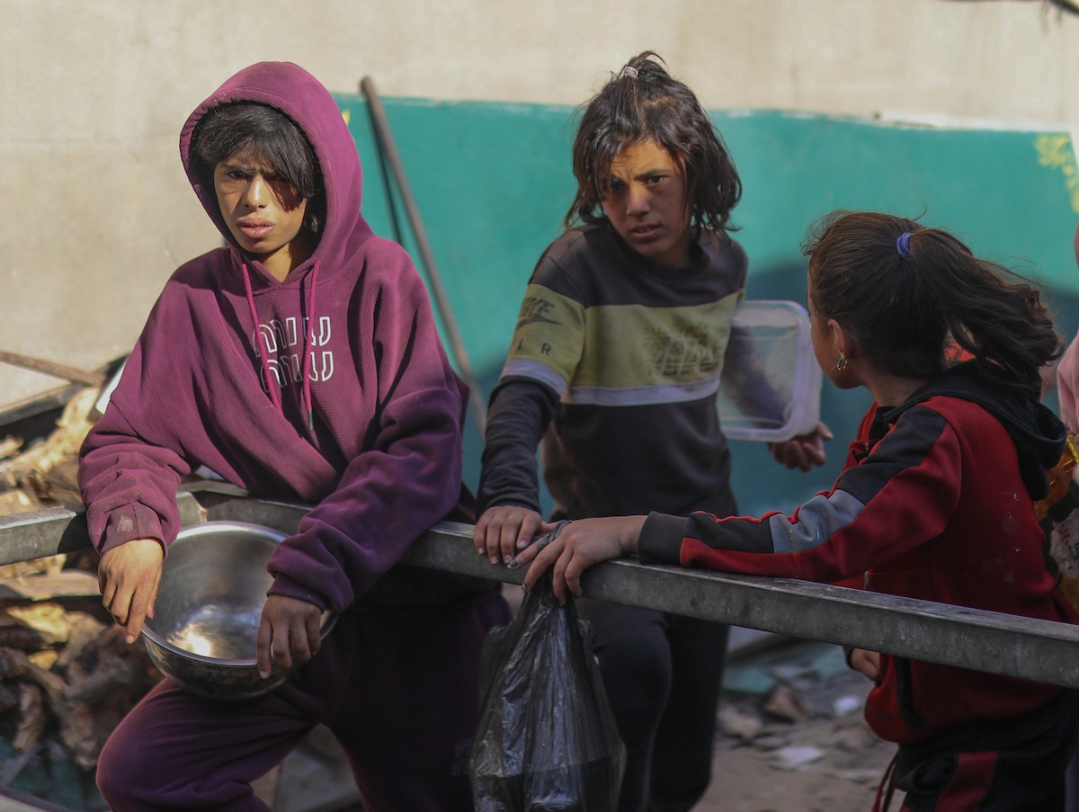 يتجمع فلسطينيون نازحون لتناول وجبة إفطارهم الرمضانية في مطبخ خيري بمخيم النصيرات للاجئين وسط قطاع غزة، في 24 فبراير/شباط 2026. ويواجه النازحون ظروفًا معيشية قاسية نتيجة انعدام الدخل ونقص المساعدات الإنسانية. (صورة: رمزي أبو عامر / apaimages)