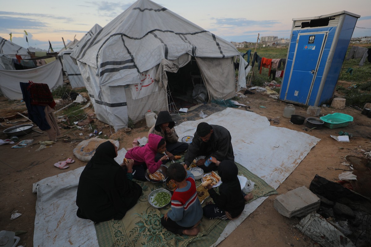 عائلة فلسطينية كفيفة تتناول وجبة الإفطار خارج خيمتها في مخيم بوسط قطاع غزة خلال شهر رمضان