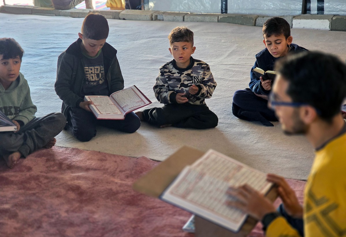 فلسطينيون، بينهم أطفال، يتلون ويحفظون القرآن الكريم خلال شهر رمضان داخل مسجد الألباني، الذي تضرر بشدة جراء الهجمات الإسرائيلية، في خان يونس، جنوب قطاع غزة، في 23 فبراير/شباط 2026. صورة: طارق محمد