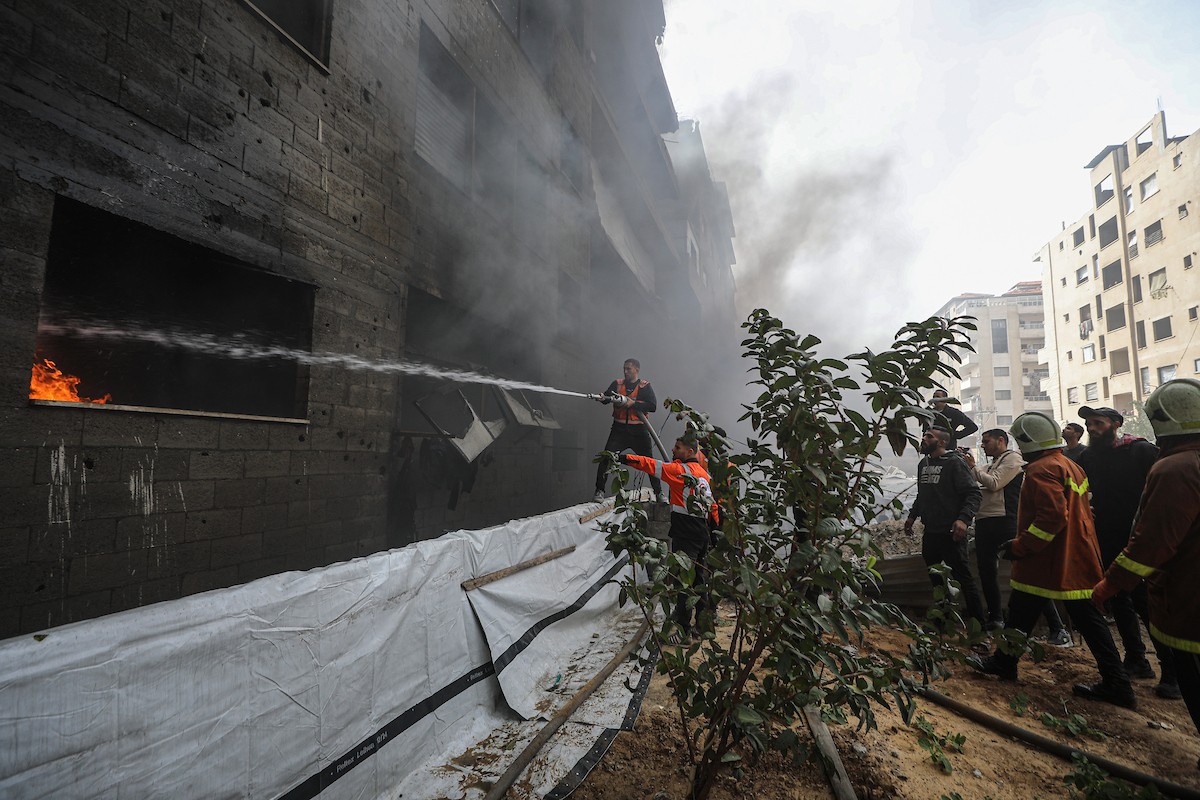 طواقم الدفاع المدني ومتطوعون من المواطنين أثناء محاولة إخماد حريق اندلع في مستودع تابع لمنظمة إغاثة في حي الرمال، غرب مدينة غزة، في 13 فبراير/شباط 2026. صورة: عمر أشتوي