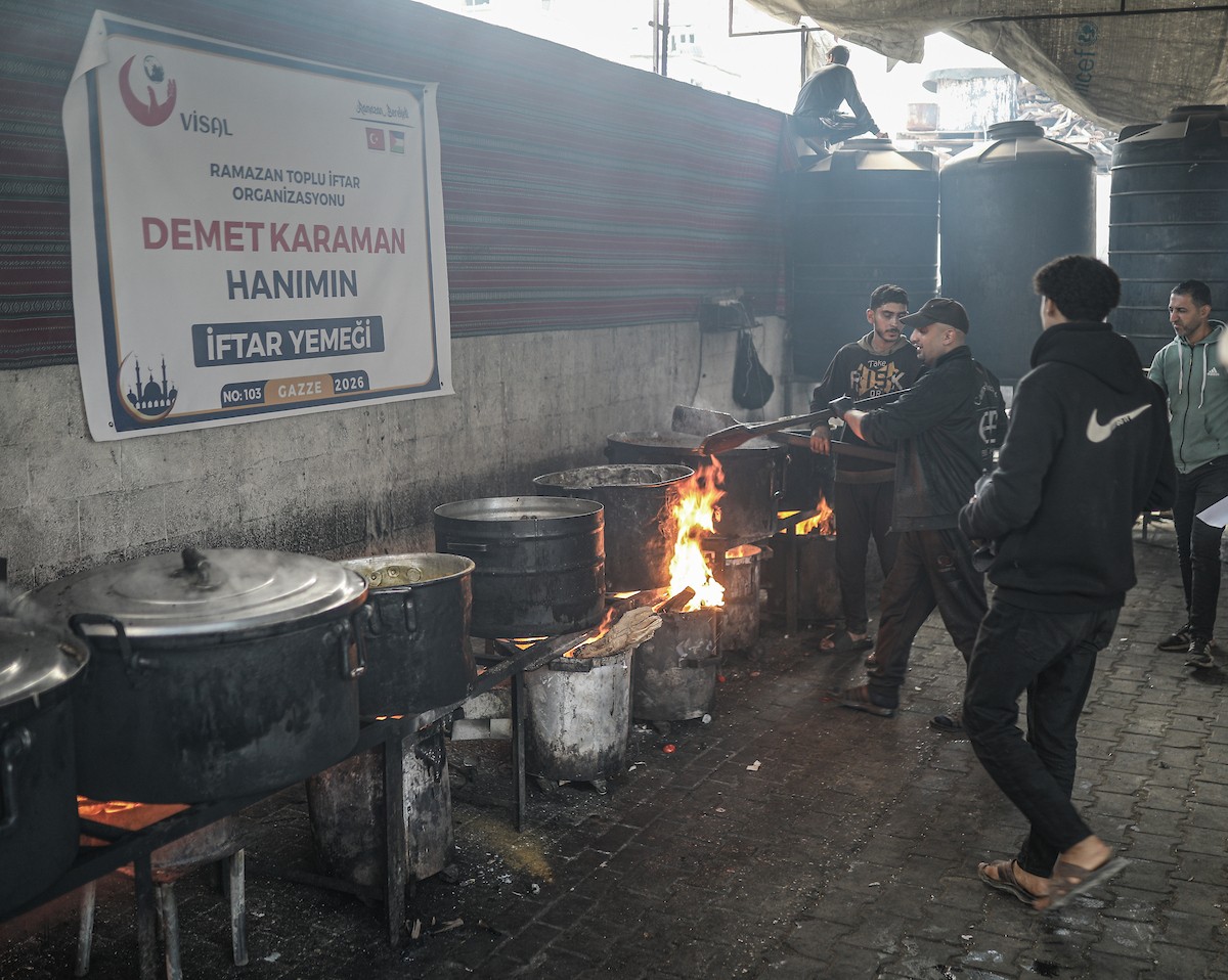 يتجمع فلسطينيون نازحون لتناول وجبة إفطارهم الرمضانية في مطبخ خيري بمخيم النصيرات للاجئين وسط قطاع غزة، في 24 فبراير/شباط 2026. ويواجه النازحون ظروفًا معيشية قاسية نتيجة انعدام الدخل ونقص المساعدات الإنسانية. (صورة: رمزي أبو عامر / apaimages)