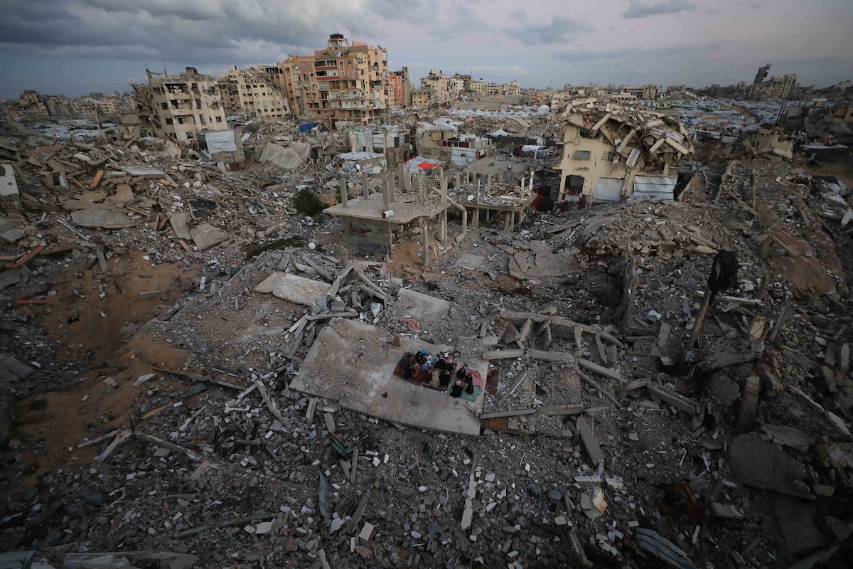 عائلة فلسطينية تتناول إفطارها خلال شهر رمضان على سطح منزلها الذي دمره قصف جوي إسرائيلي خلال حرب غزة في 27 فبراير/شباط 2026. صورة: عمر أشتوي