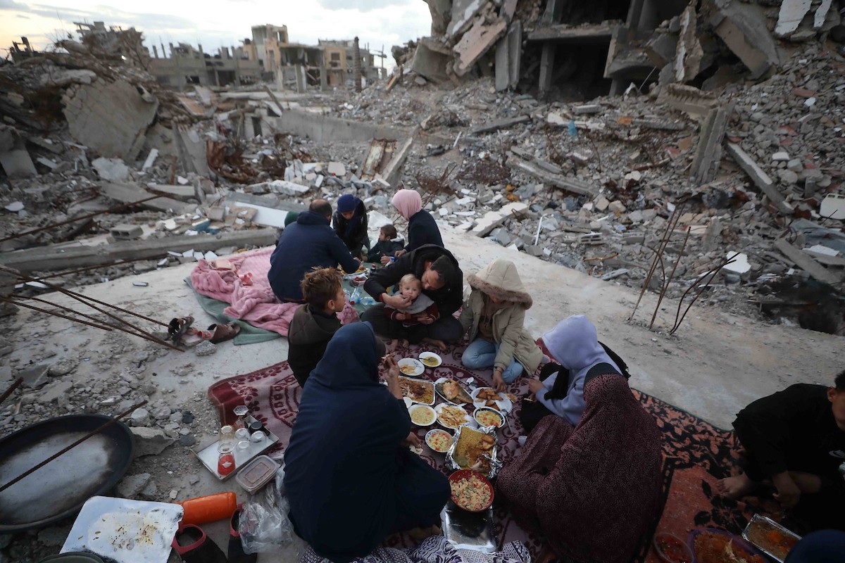 عائلة فلسطينية تتناول إفطارها خلال شهر رمضان على سطح منزلها الذي دمره قصف جوي إسرائيلي خلال حرب غزة في 27 فبراير/شباط 2026. صورة: عمر أشتوي