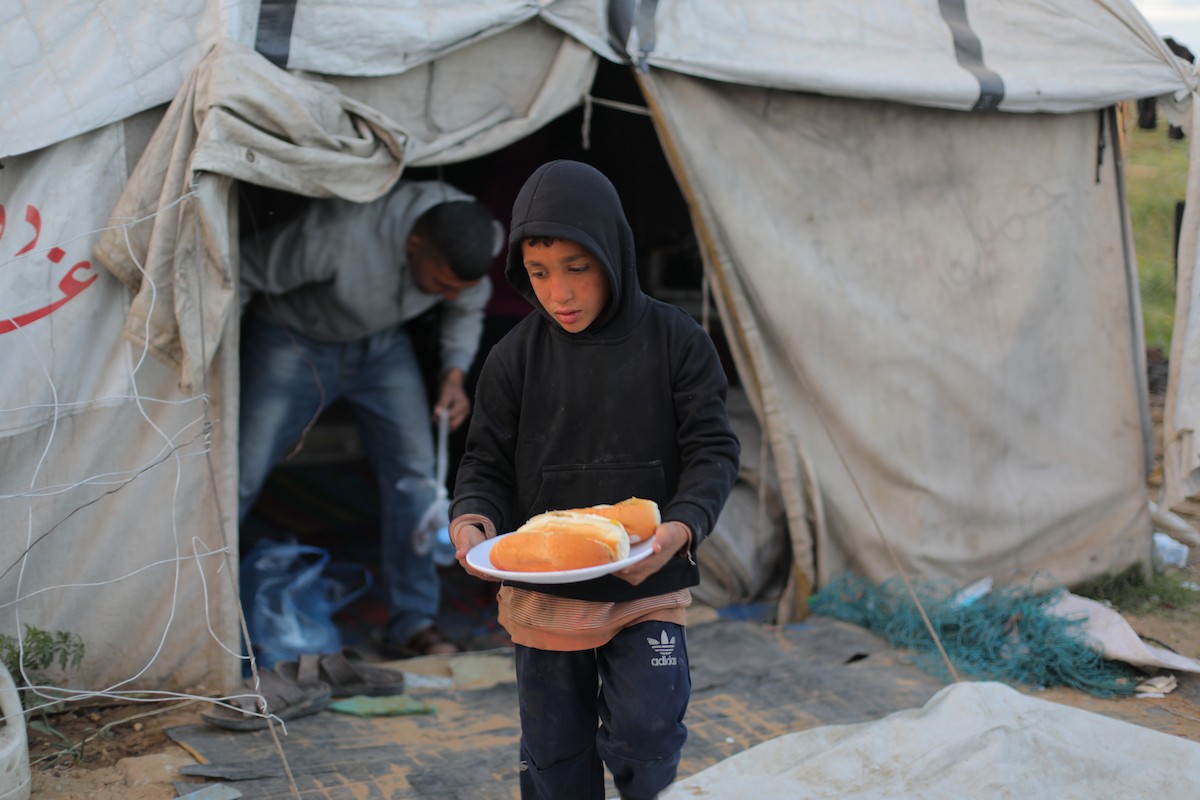 عائلة فلسطينية كفيفة تتناول وجبة الإفطار خارج خيمتها في مخيم بوسط قطاع غزة خلال شهر رمضان