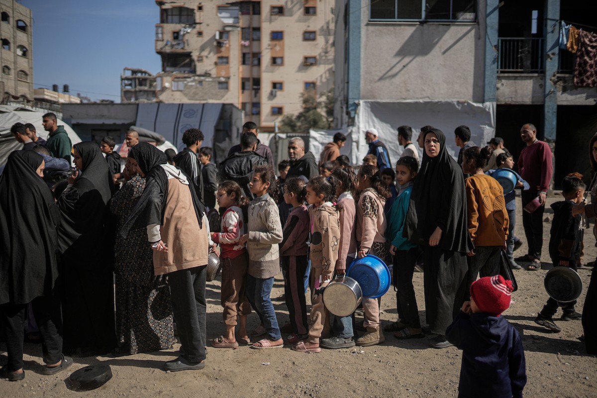 فلسطينيون بينهم أطفال ونساء يتلقون مساعدات غذائية وزعتها منظمات خيرية في أحد مراكز الإيواء بمدينة غزة، وسط أزمة غذائية مستمرة ناجمة عن محدودية المساعدات الإنسانية والظروف الإنسانية المتردية التي يواجهها النازحون، ١٢ فبراير/شباط ٢٠٢٦. تصوير: عمر أشتوي