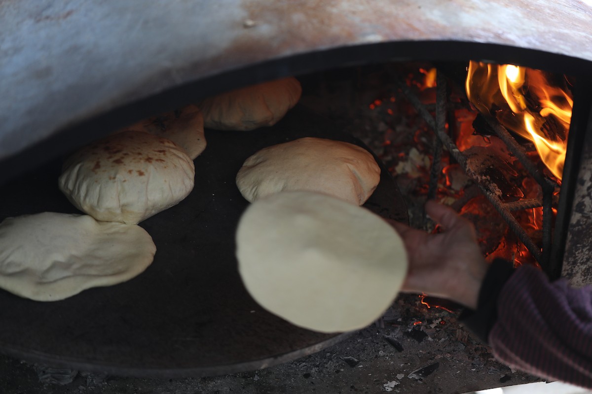 مجموعة من النساء يعملن داخل مخبز أُنشئ في مخيم اليرموك للاجئين بمدينة غزة، ضمن مبادرة إنسانية بالشراكة مع اللجنة الدولية للصليب الأحمر. تهدف المبادرة إلى تخفيف الأعباء المعيشية عن النساء النازحات، لا سيما خلال شهر رمضان. مدينة غزة، 25 فبراير/شباط 2026. تصوير: عمر أشتوي