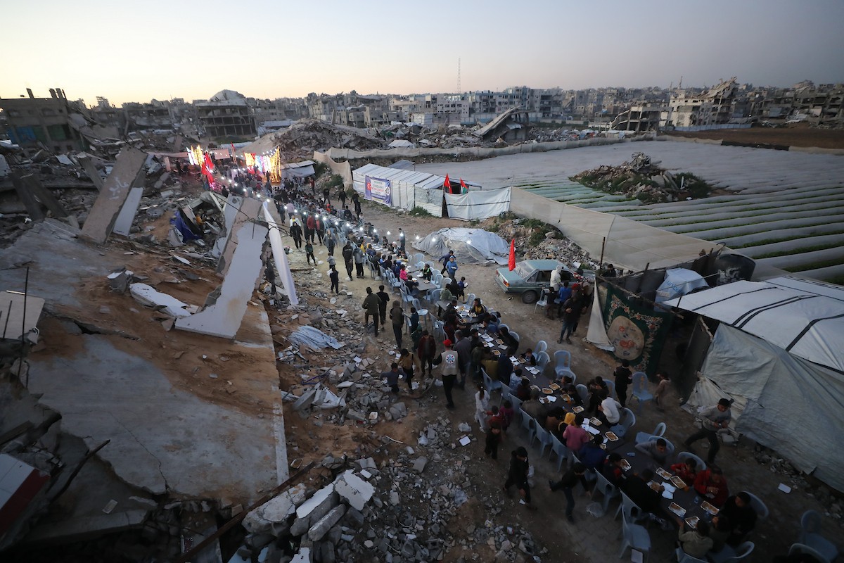 يتجمع فلسطينيون نازحون لتناول وجبة الإفطار وسط أنقاض المباني المدمرة في مدينة غزة، خلال شهر رمضان المبارك، في 25 فبراير/شباط 2026. صورة: عمر أشتوي