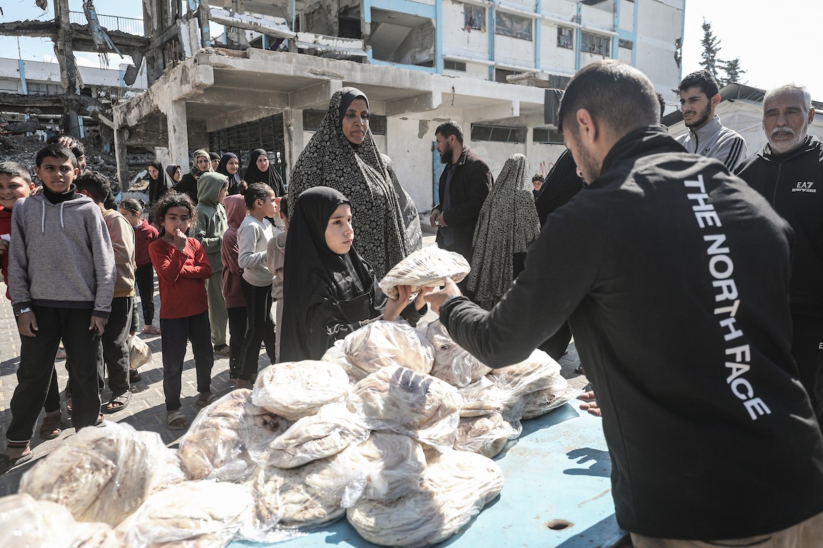 نساء فلسطينيات، زوجات شهداء الحرب، يُجهّزن الخبز لتوزيعه على العائلات النازحة والمحتاجة في مخيم البريج للاجئين وسط قطاع غزة خلال شهر رمضان، في مشهد يُجسّد روح التضامن والصمود في ظلّ الظروف الإنسانية الصعبة، فبراير/شباط 2026. تصوير: معز صالحي
