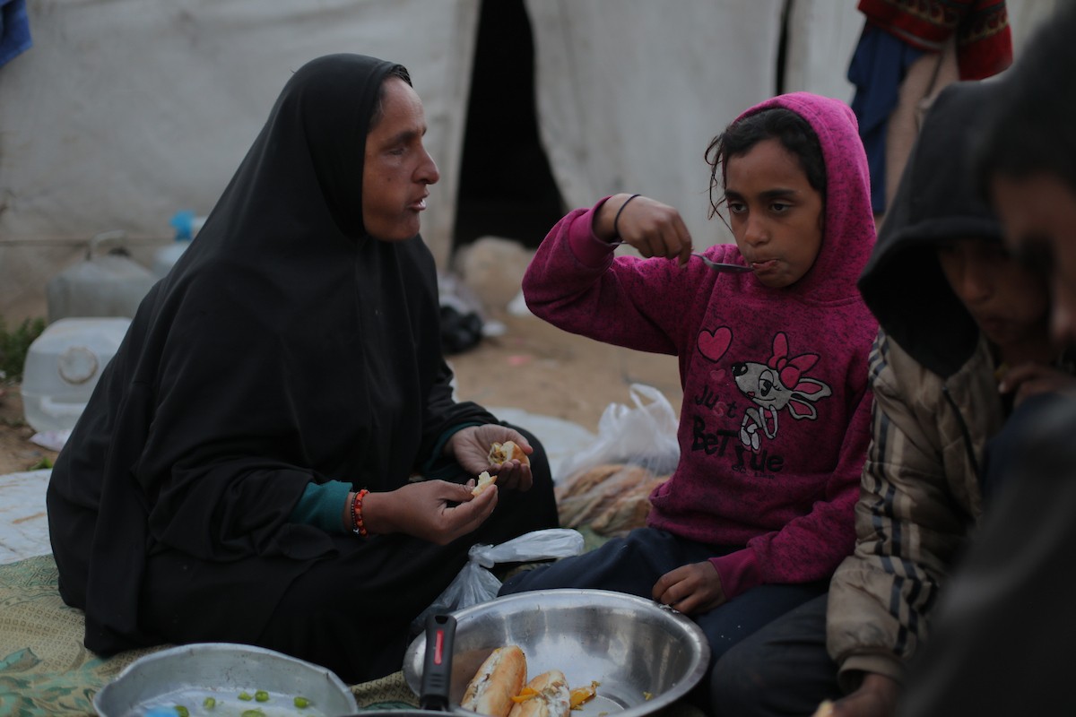 عائلة فلسطينية كفيفة تتناول وجبة الإفطار خارج خيمتها في مخيم بوسط قطاع غزة خلال شهر رمضان