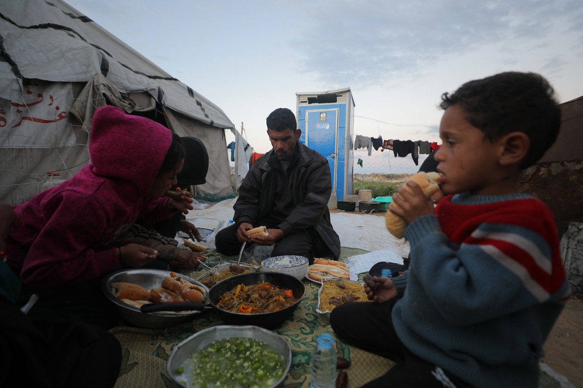 عائلة فلسطينية كفيفة تتناول وجبة الإفطار خارج خيمتها في مخيم بوسط قطاع غزة خلال شهر رمضان