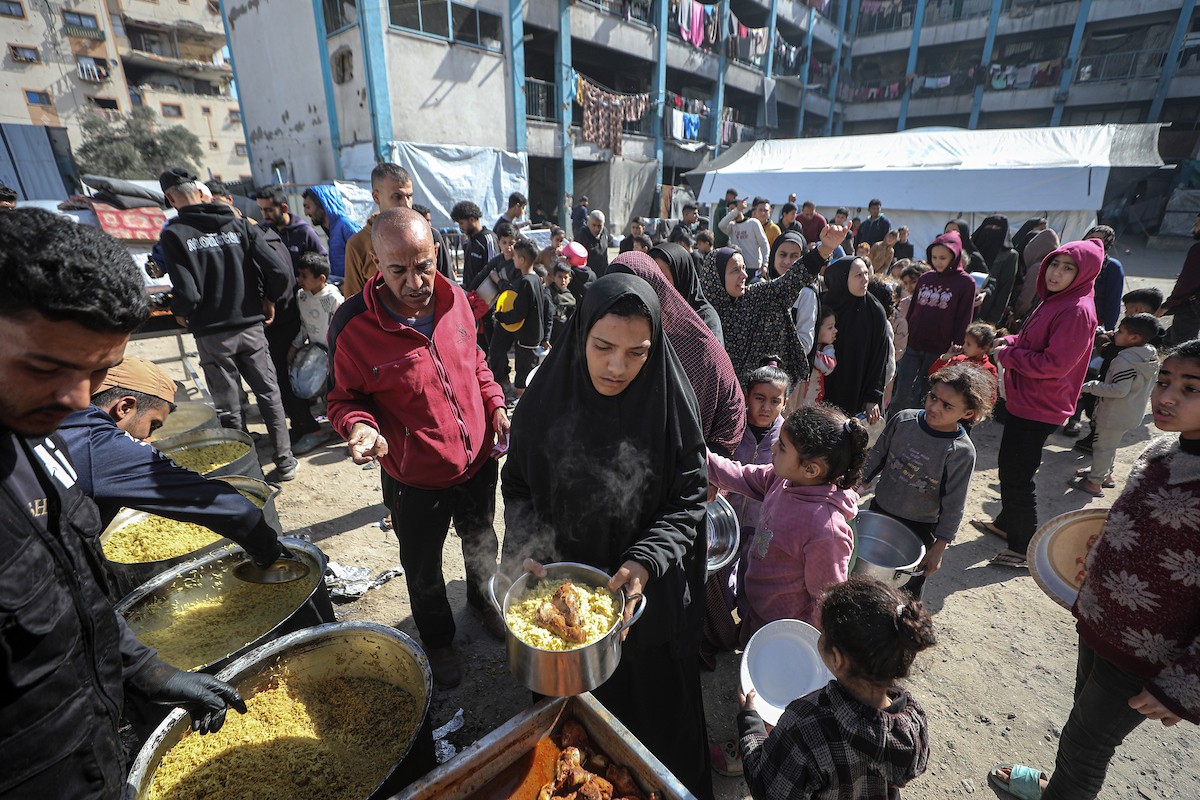 فلسطينيون بينهم أطفال ونساء يتلقون مساعدات غذائية وزعتها منظمات خيرية في أحد مراكز الإيواء بمدينة غزة، وسط أزمة غذائية مستمرة ناجمة عن محدودية المساعدات الإنسانية والظروف الإنسانية المتردية التي يواجهها النازحون، ١٢ فبراير/شباط ٢٠٢٦. تصوير: عمر أشتوي