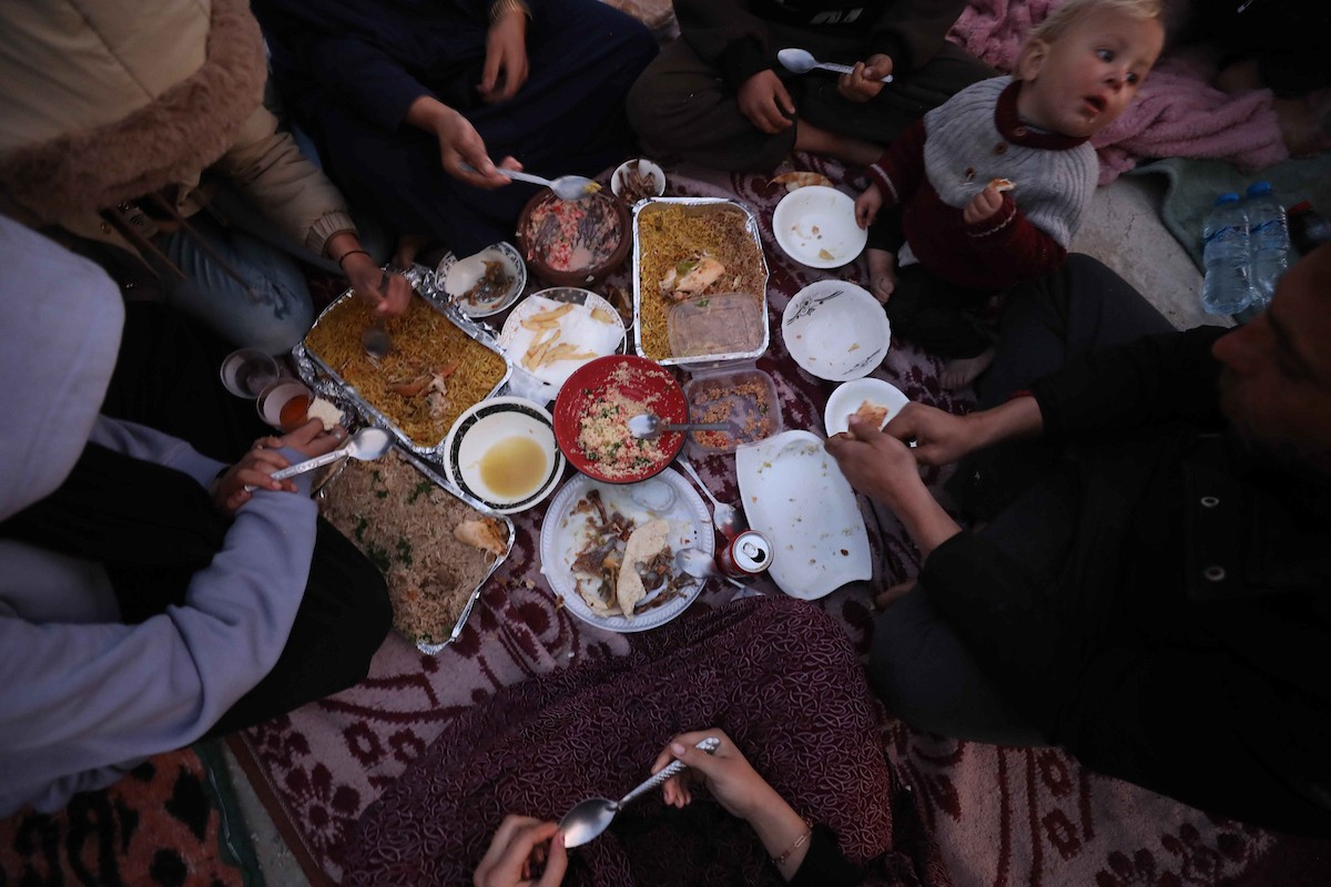 عائلة فلسطينية تتناول إفطارها خلال شهر رمضان على سطح منزلها الذي دمره قصف جوي إسرائيلي خلال حرب غزة في 27 فبراير/شباط 2026. صورة: عمر أشتوي
