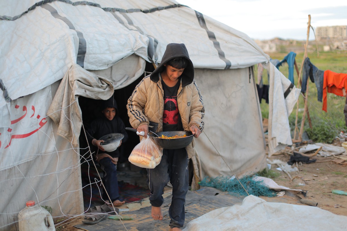 عائلة فلسطينية كفيفة تتناول وجبة الإفطار خارج خيمتها في مخيم بوسط قطاع غزة خلال شهر رمضان
