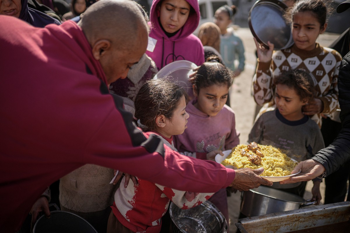 فلسطينيون بينهم أطفال ونساء يتلقون مساعدات غذائية وزعتها منظمات خيرية في أحد مراكز الإيواء بمدينة غزة، وسط أزمة غذائية مستمرة ناجمة عن محدودية المساعدات الإنسانية والظروف الإنسانية المتردية التي يواجهها النازحون، ١٢ فبراير/شباط ٢٠٢٦. تصوير: عمر أشتوي