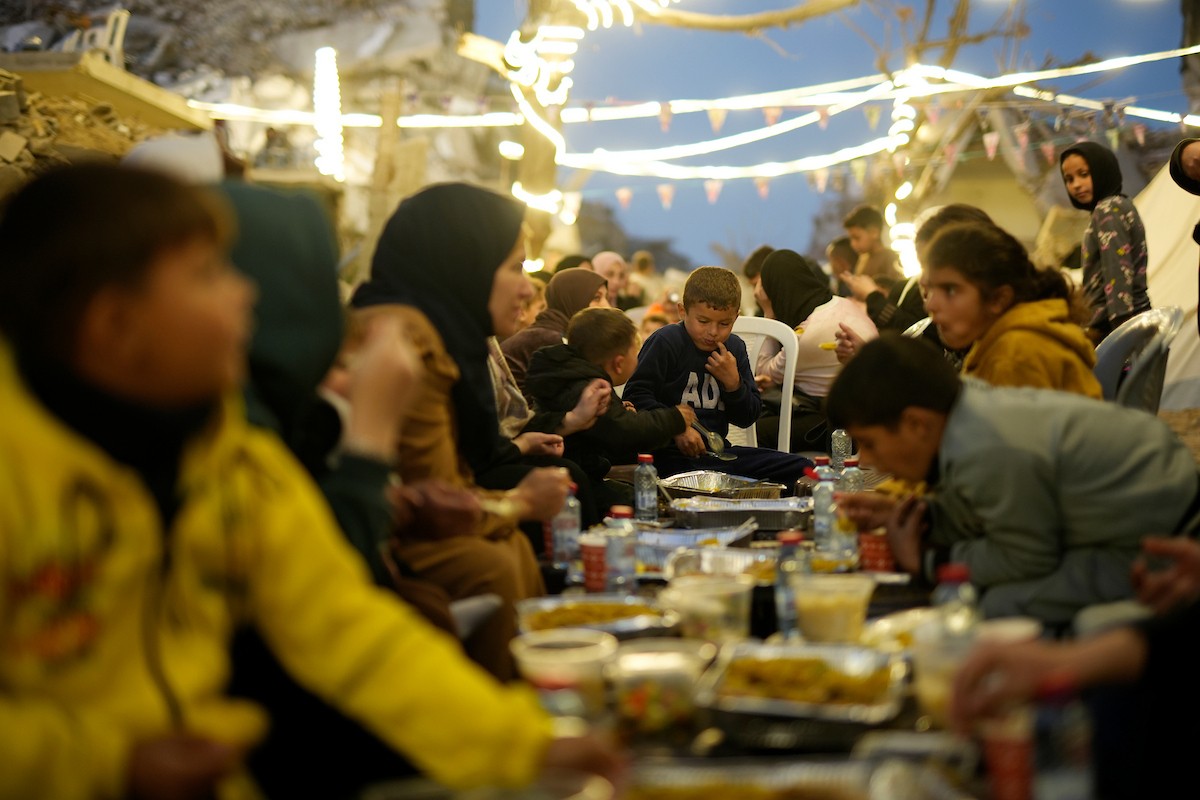 يتجمع الفلسطينيون بين المنازل المدمرة لتناول وجبة الإفطار معًا خلال شهر رمضان المبارك في شمال قطاع غزة، 22 فبراير/شباط 2026. صورة: عمر أشتوي