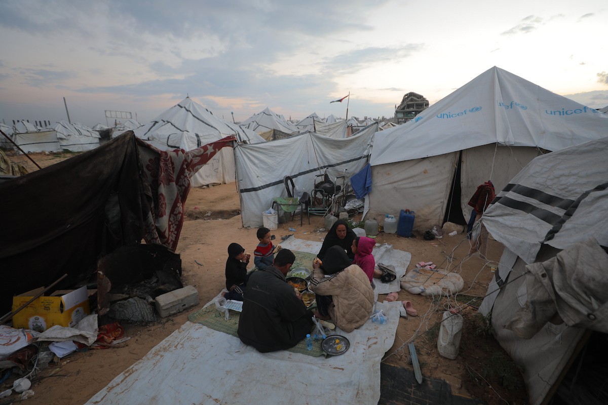 عائلة فلسطينية كفيفة تتناول وجبة الإفطار خارج خيمتها في مخيم بوسط قطاع غزة خلال شهر رمضان