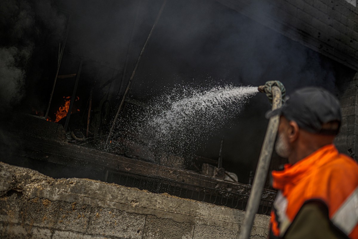 طواقم الدفاع المدني ومتطوعون من المواطنين أثناء محاولة إخماد حريق اندلع في مستودع تابع لمنظمة إغاثة في حي الرمال، غرب مدينة غزة، في 13 فبراير/شباط 2026. صورة: عمر أشتوي