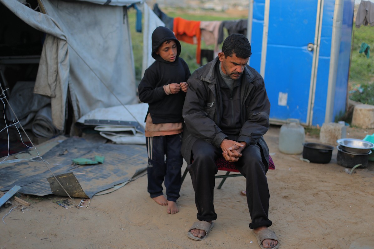 عائلة فلسطينية كفيفة تتناول وجبة الإفطار خارج خيمتها في مخيم بوسط قطاع غزة خلال شهر رمضان