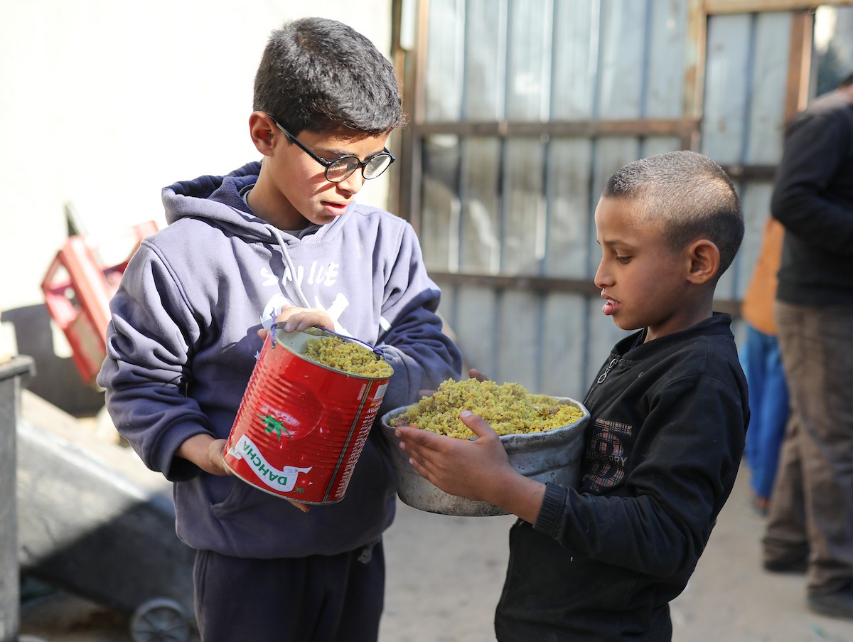 يتجمع فلسطينيون نازحون لتناول وجبة إفطارهم الرمضانية في مطبخ خيري بمخيم النصيرات للاجئين وسط قطاع غزة، في 24 فبراير/شباط 2026. ويواجه النازحون ظروفًا معيشية قاسية نتيجة انعدام الدخل ونقص المساعدات الإنسانية. (صورة: رمزي أبو عامر / apaimages)