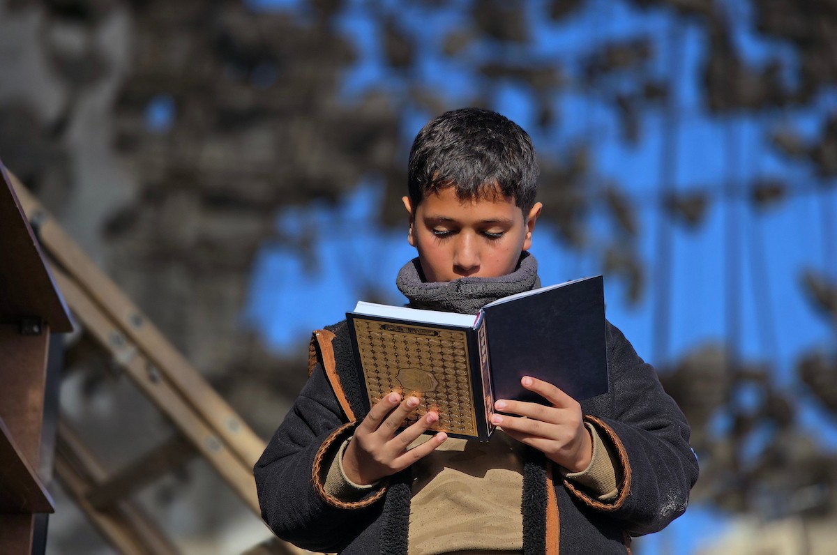 فلسطينيون، بينهم أطفال، يتلون ويحفظون القرآن الكريم خلال شهر رمضان داخل مسجد الألباني، الذي تضرر بشدة جراء الهجمات الإسرائيلية، في خان يونس، جنوب قطاع غزة، في 23 فبراير/شباط 2026. صورة: طارق محمد