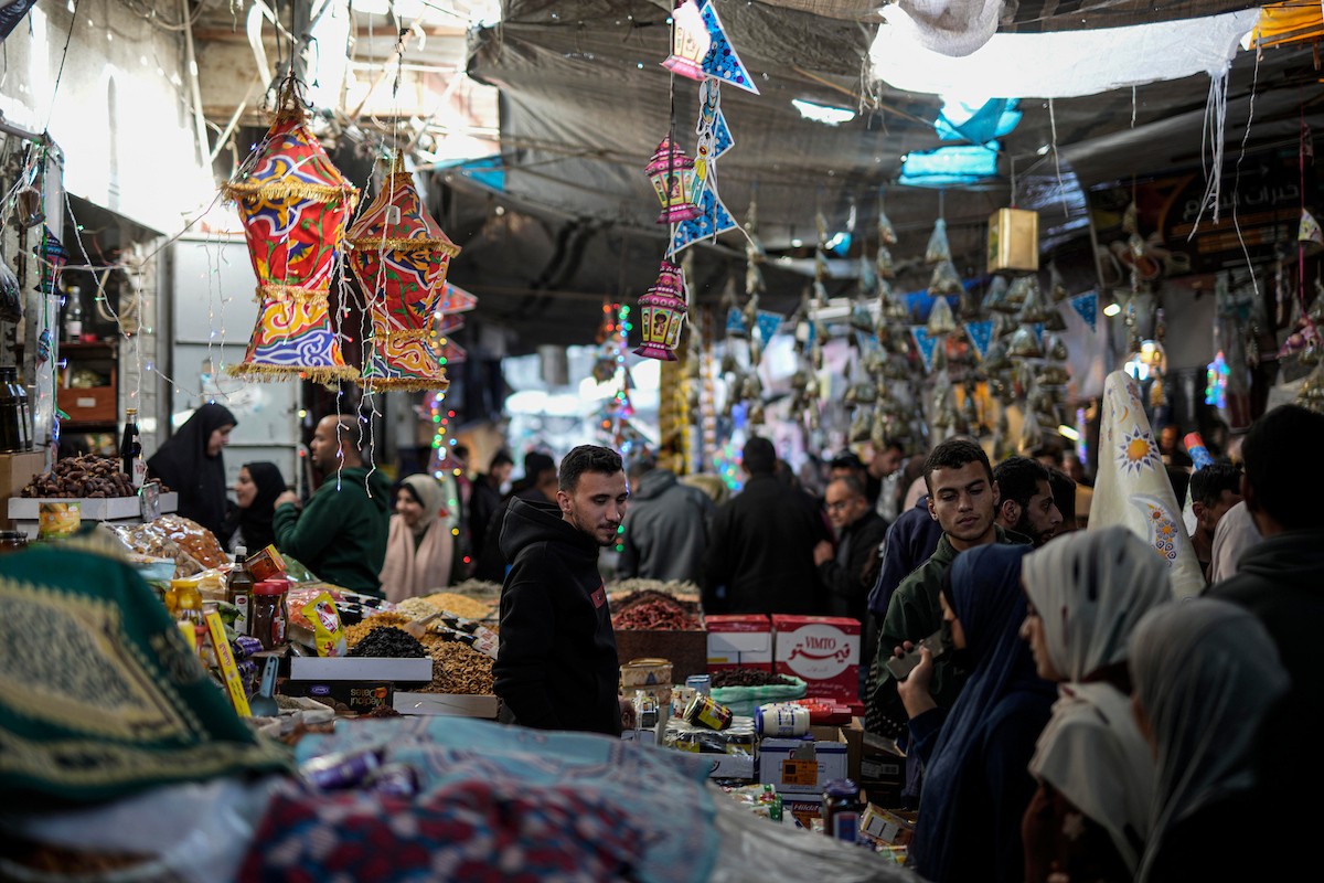 يتسوق الفلسطينيون في أول ليلة من شهر رمضان المبارك في سوق الزاوية، الواقع في قلب مدينة غزة والذي تضرر بشدة جراء الحرب الإسرائيلية. يعرض الباعة بضائعهم على أكشاك مزينة بالفوانيس والأضواء وأطعمة رمضان. مدينة غزة، 17 فبراير/شباط 2026. تصوير: عمر أشتوي