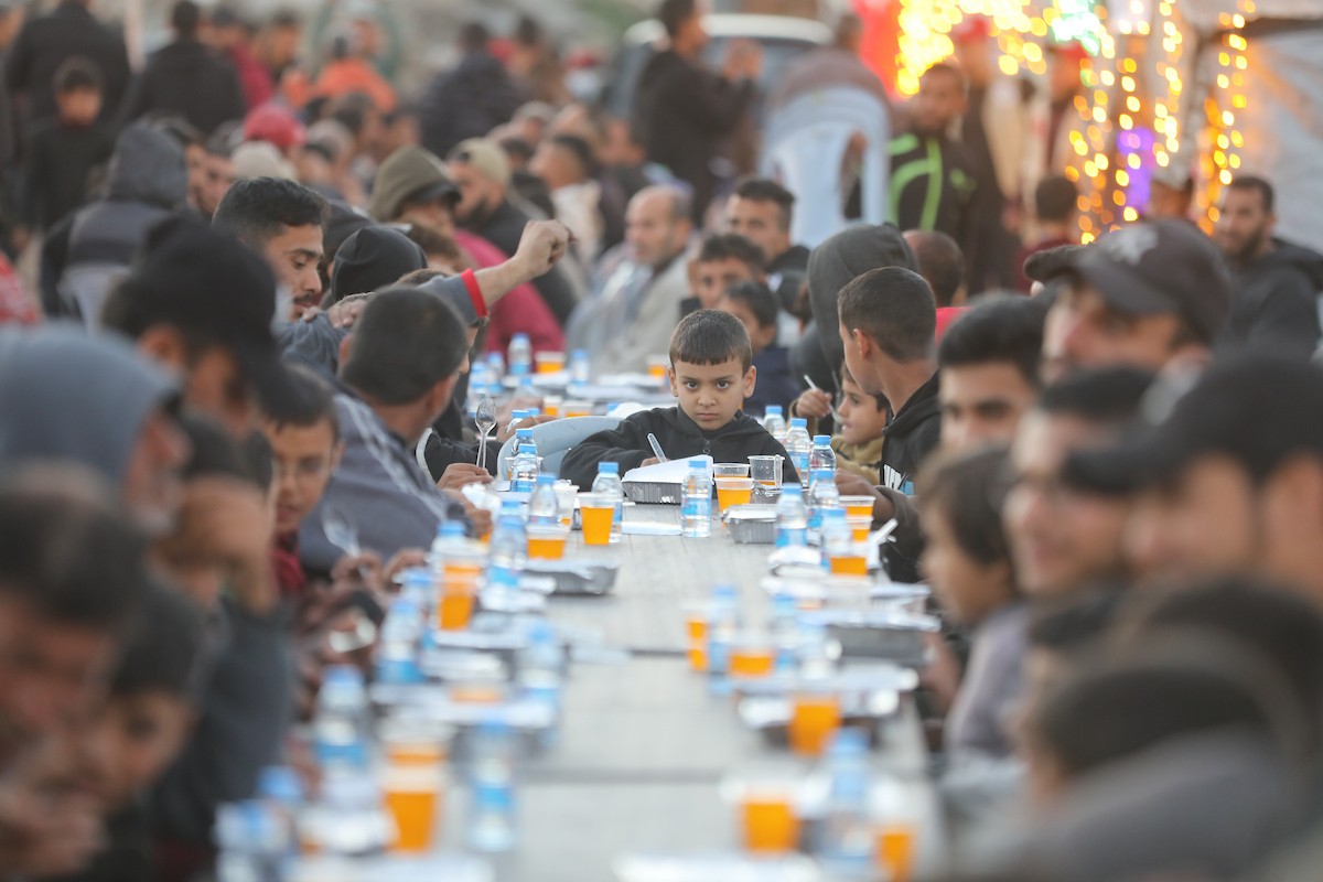 يتجمع فلسطينيون نازحون لتناول وجبة الإفطار وسط أنقاض المباني المدمرة في مدينة غزة، خلال شهر رمضان المبارك، في 25 فبراير/شباط 2026. صورة: عمر أشتوي