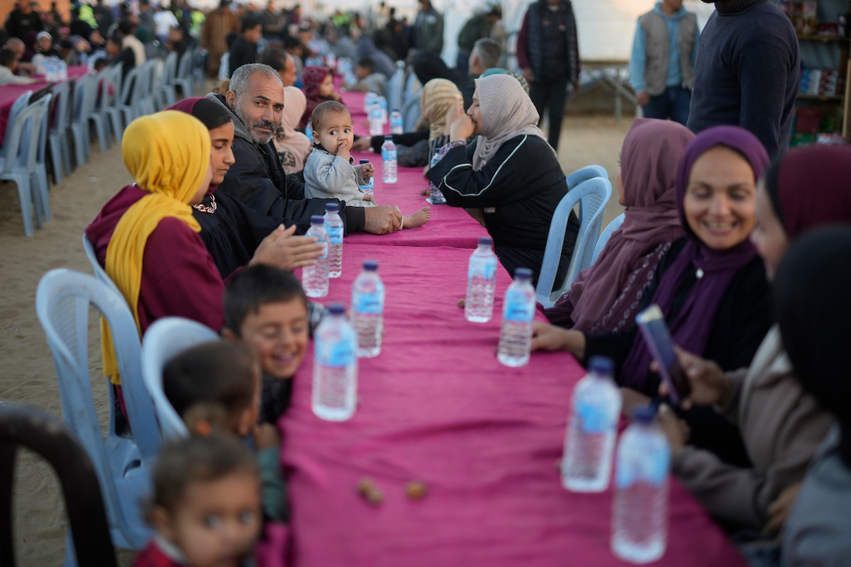 يتجمع فلسطينيون نازحون لتناول وجبة الإفطار، وهي وجبة كسر الصيام، خلال شهر رمضان المبارك في مخيم خيام يؤويهم، بحي الزهراء وسط قطاع غزة، يوم السبت 21 فبراير/شباط 2026. تصوير: عمر أشتوي