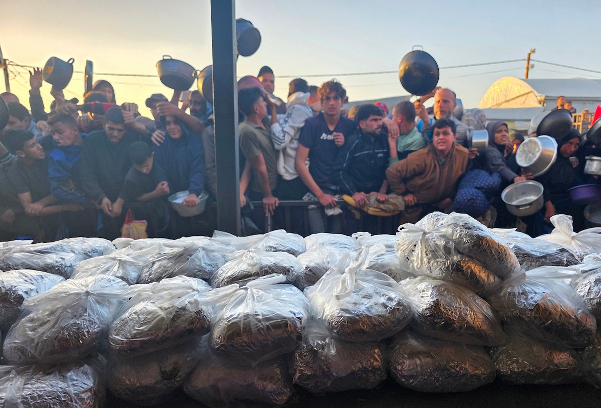 فلسطينيون نازحون يكافحون للحصول على طعام مُتبرع به للإفطار، وجبة كسر الصيام، في اليوم الرابع من شهر رمضان المبارك في مطبخ مجتمعي في خان يونس، قطاع غزة، 21 فبراير/شباط 2026. تصوير: طارق محمد/(APA Images)