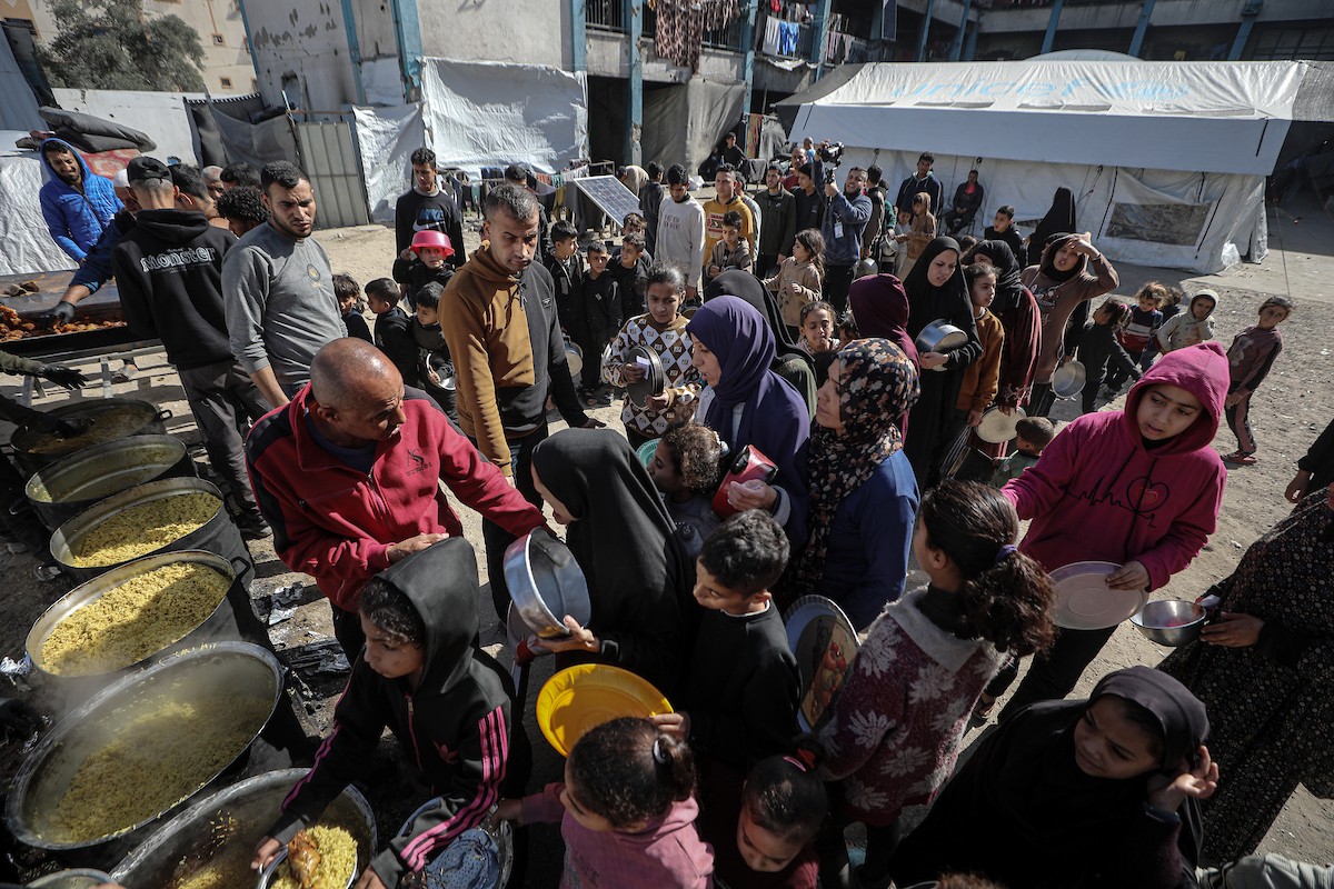 فلسطينيون بينهم أطفال ونساء يتلقون مساعدات غذائية وزعتها منظمات خيرية في أحد مراكز الإيواء بمدينة غزة، وسط أزمة غذائية مستمرة ناجمة عن محدودية المساعدات الإنسانية والظروف الإنسانية المتردية التي يواجهها النازحون، ١٢ فبراير/شباط ٢٠٢٦. تصوير: عمر أشتوي