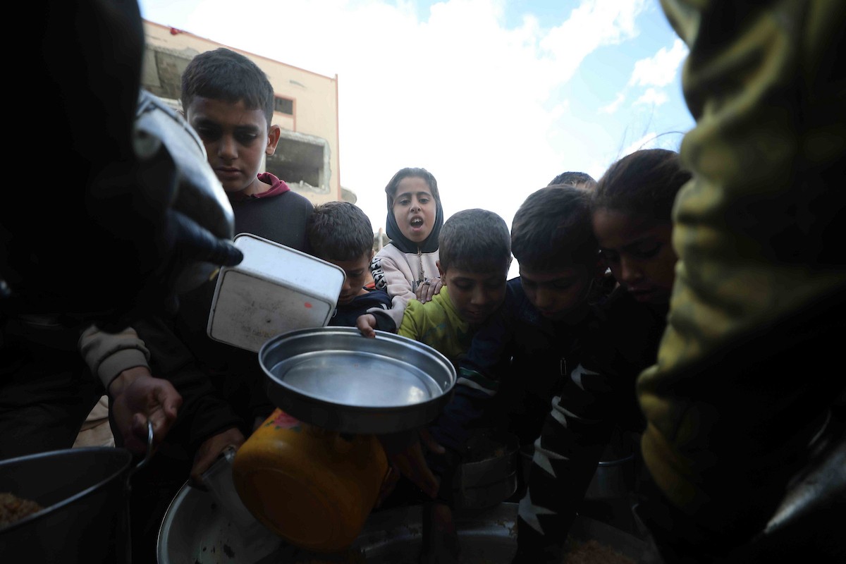 تجمع فلسطينيون نازحون، بينهم أطفال ونساء، حاملين أوعية طعام لتلقي وجبات ساخنة وزعتها جمعيات خيرية قبل الإفطار في مدينة غزة في 27 فبراير/شباط 2026.صورة: عمر أشتوي