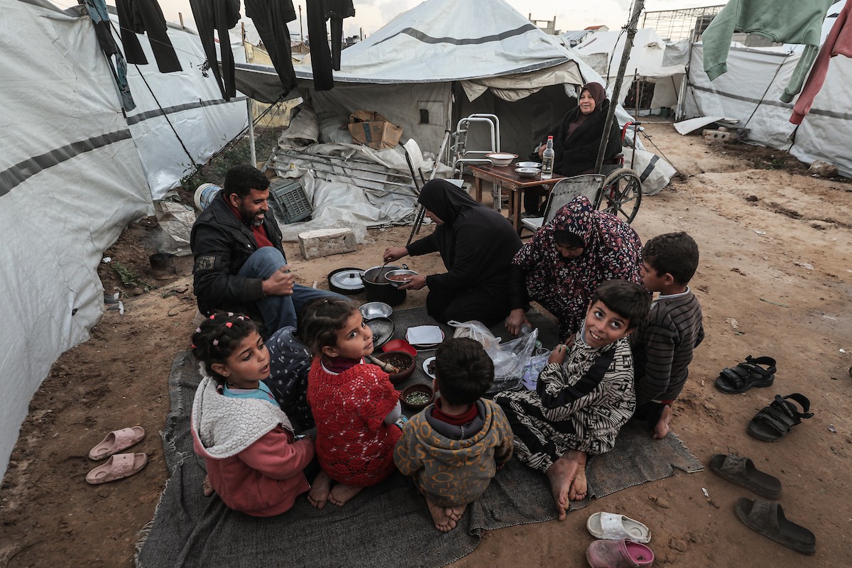 عائلة فلسطينية نازحة تتناول فطورها خلال شهر رمضان داخل خيمة متداعية في مخيم النصيرات للاجئين وسط قطاع غزة. تواجه العائلات النازحة ظروفًا معيشية قاسية نتيجة الحرب، مع انعدام الدخل ونقص حاد في المساعدات الإنسانية، 26 فبراير/شباط 2026. تصوير: معز صالحي