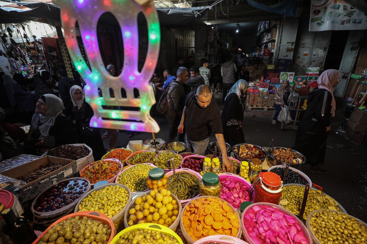 يتسوق الفلسطينيون في أول ليلة من شهر رمضان المبارك في سوق الزاوية، الواقع في قلب مدينة غزة والذي تضرر بشدة جراء الحرب الإسرائيلية. يعرض الباعة بضائعهم على أكشاك مزينة بالفوانيس والأضواء وأطعمة رمضان. مدينة غزة، 17 فبراير/شباط 2026. تصوير: عمر أشتوي