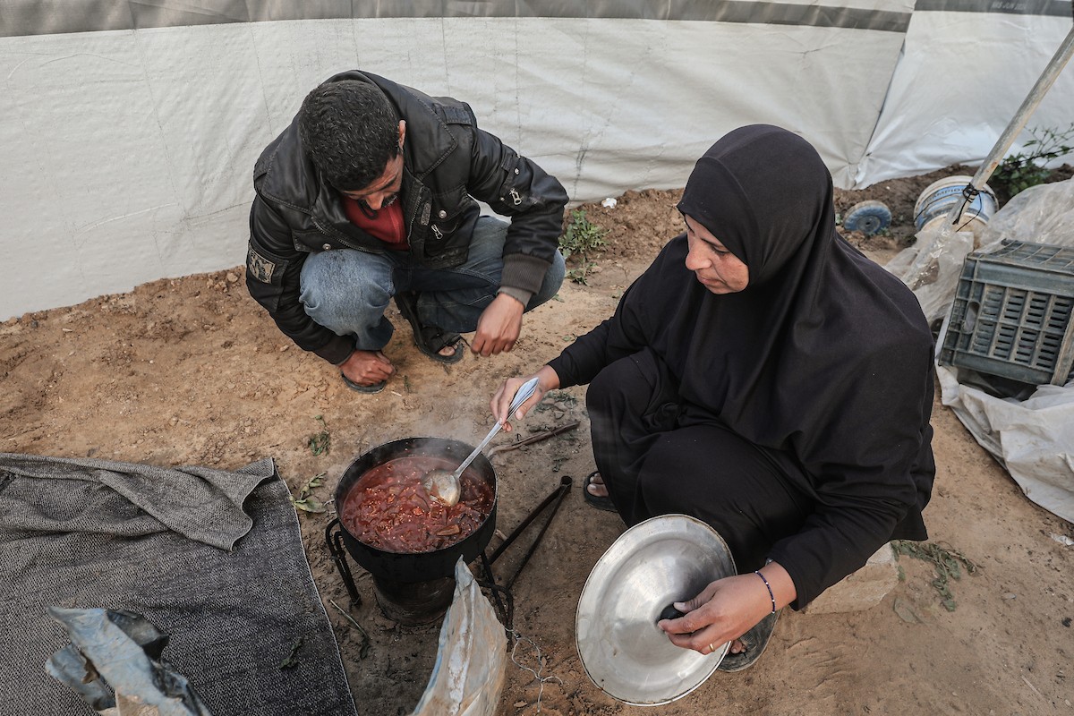 عائلة فلسطينية نازحة تتناول فطورها خلال شهر رمضان داخل خيمة متداعية في مخيم النصيرات للاجئين وسط قطاع غزة. تواجه العائلات النازحة ظروفًا معيشية قاسية نتيجة الحرب، مع انعدام الدخل ونقص حاد في المساعدات الإنسانية، 26 فبراير/شباط 2026. تصوير: معز صالحي