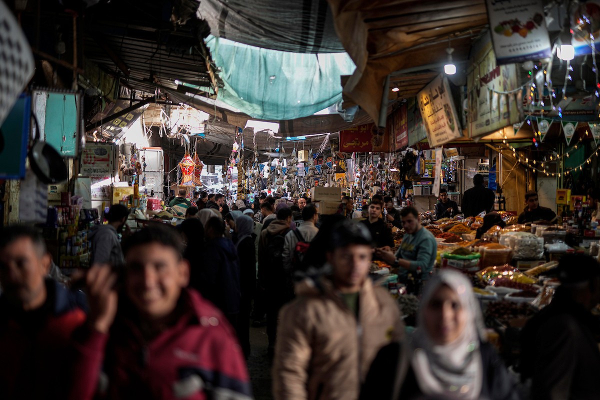 يتسوق الفلسطينيون في أول ليلة من شهر رمضان المبارك في سوق الزاوية، الواقع في قلب مدينة غزة والذي تضرر بشدة جراء الحرب الإسرائيلية. يعرض الباعة بضائعهم على أكشاك مزينة بالفوانيس والأضواء وأطعمة رمضان. مدينة غزة، 17 فبراير/شباط 2026. تصوير: عمر أشتوي
