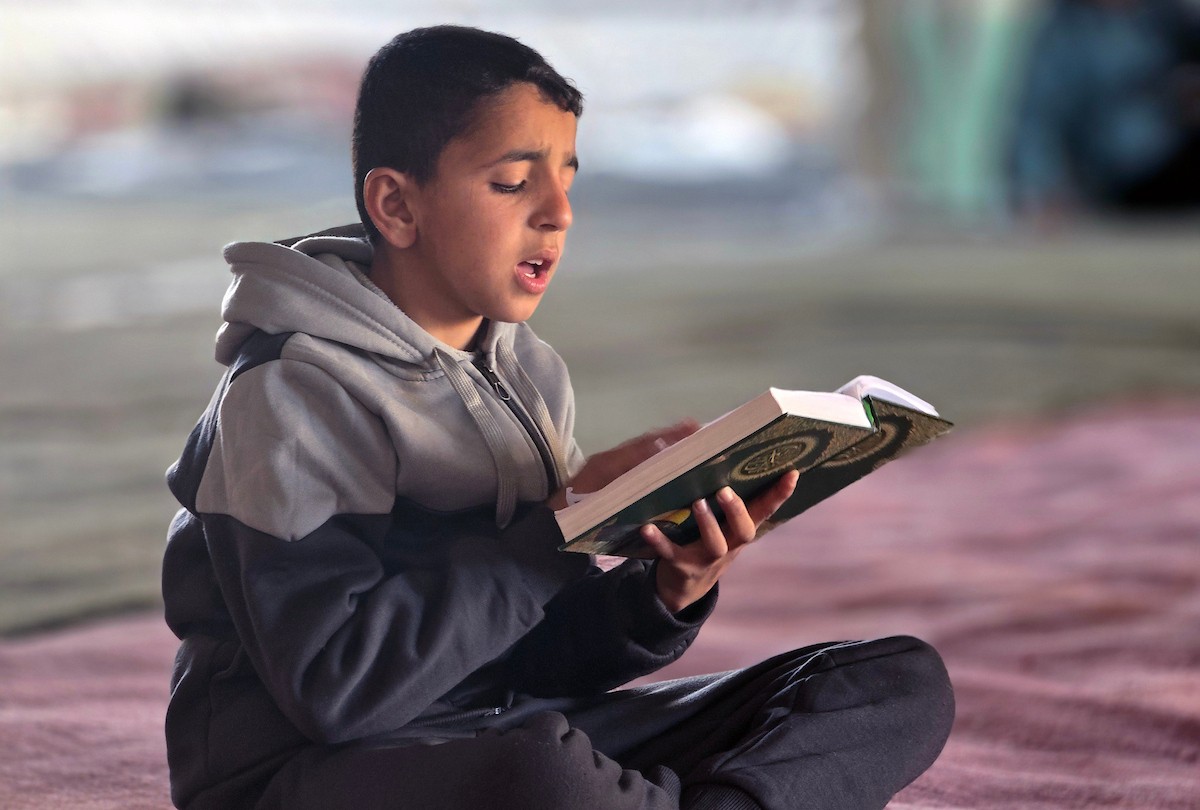 فلسطينيون، بينهم أطفال، يتلون ويحفظون القرآن الكريم خلال شهر رمضان داخل مسجد الألباني، الذي تضرر بشدة جراء الهجمات الإسرائيلية، في خان يونس، جنوب قطاع غزة، في 23 فبراير/شباط 2026. صورة: طارق محمد