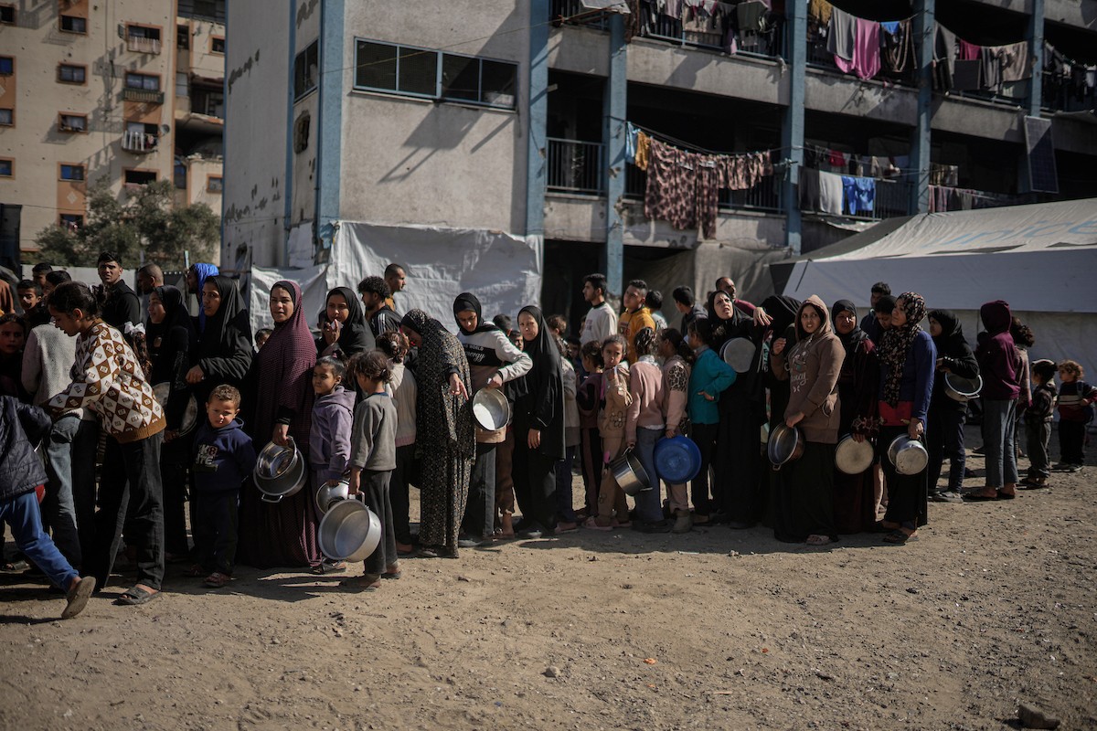 فلسطينيون بينهم أطفال ونساء يتلقون مساعدات غذائية وزعتها منظمات خيرية في أحد مراكز الإيواء بمدينة غزة، وسط أزمة غذائية مستمرة ناجمة عن محدودية المساعدات الإنسانية والظروف الإنسانية المتردية التي يواجهها النازحون، ١٢ فبراير/شباط ٢٠٢٦. تصوير: عمر أشتوي