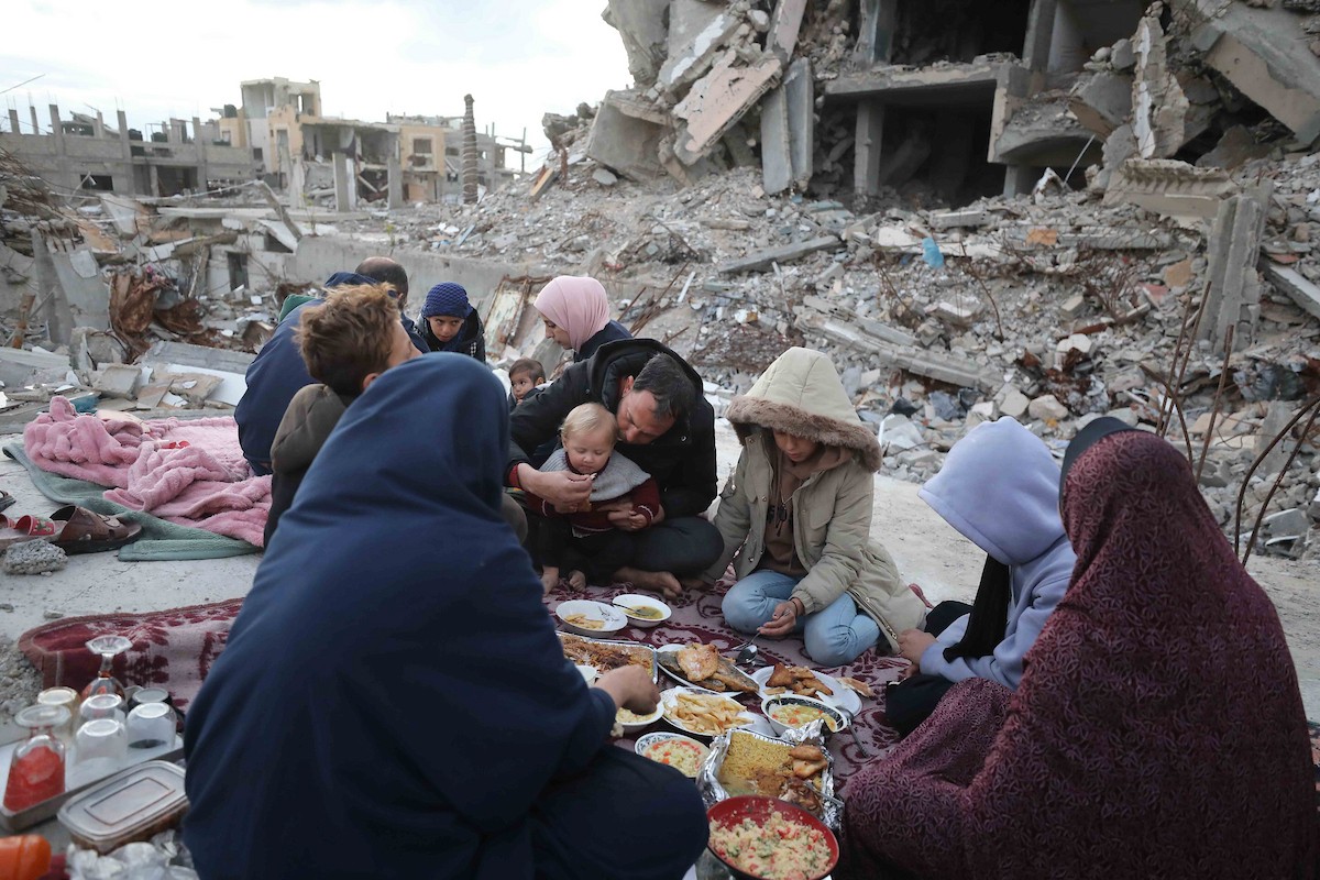 عائلة فلسطينية تتناول إفطارها خلال شهر رمضان على سطح منزلها الذي دمره قصف جوي إسرائيلي خلال حرب غزة في 27 فبراير/شباط 2026. صورة: عمر أشتوي