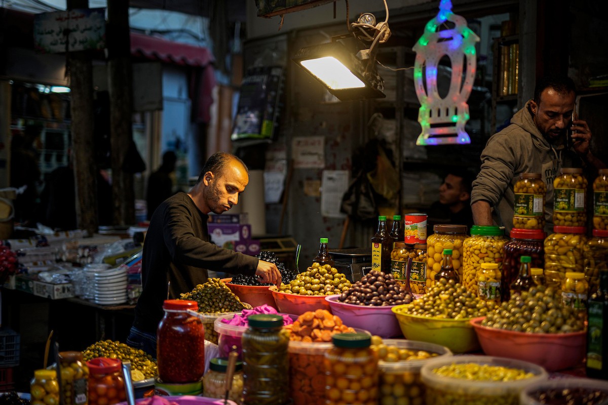 يتسوق الفلسطينيون في أول ليلة من شهر رمضان المبارك في سوق الزاوية، الواقع في قلب مدينة غزة والذي تضرر بشدة جراء الحرب الإسرائيلية. يعرض الباعة بضائعهم على أكشاك مزينة بالفوانيس والأضواء وأطعمة رمضان. مدينة غزة، 17 فبراير/شباط 2026. تصوير: عمر أشتوي
