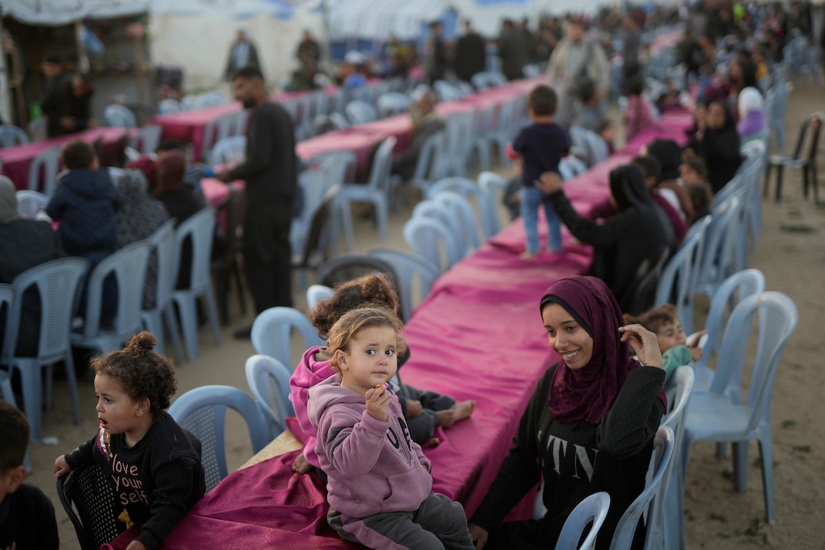 يتجمع فلسطينيون نازحون لتناول وجبة الإفطار، وهي وجبة كسر الصيام، خلال شهر رمضان المبارك في مخيم خيام يؤويهم، بحي الزهراء وسط قطاع غزة، يوم السبت 21 فبراير/شباط 2026. تصوير: عمر أشتوي