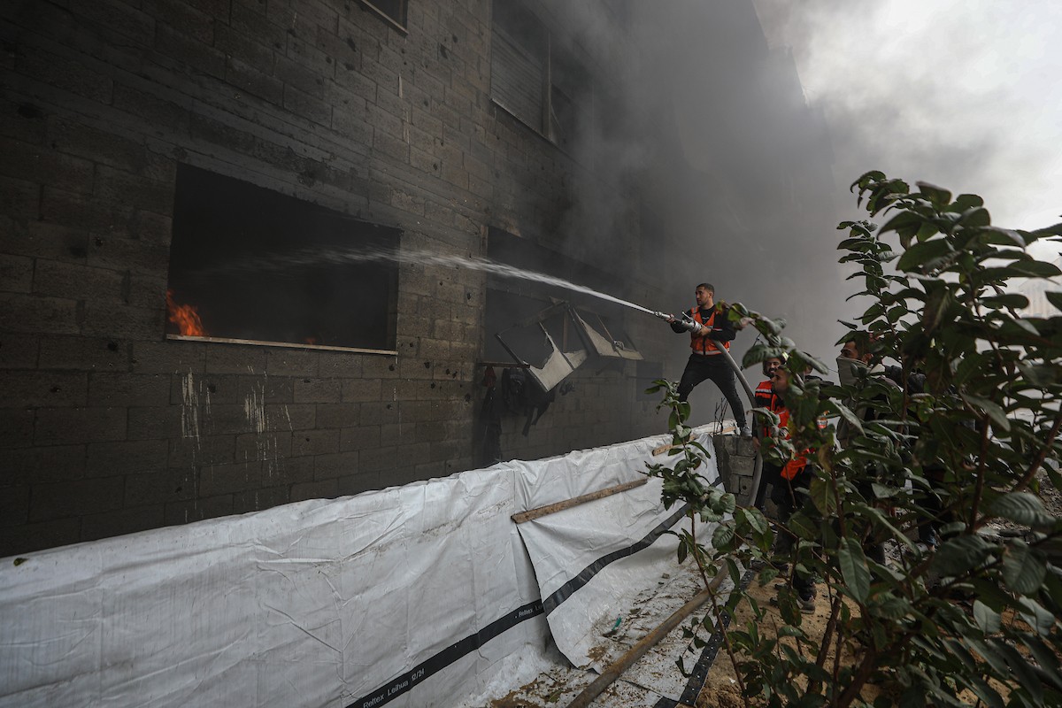 طواقم الدفاع المدني ومتطوعون من المواطنين أثناء محاولة إخماد حريق اندلع في مستودع تابع لمنظمة إغاثة في حي الرمال، غرب مدينة غزة، في 13 فبراير/شباط 2026. صورة: عمر أشتوي