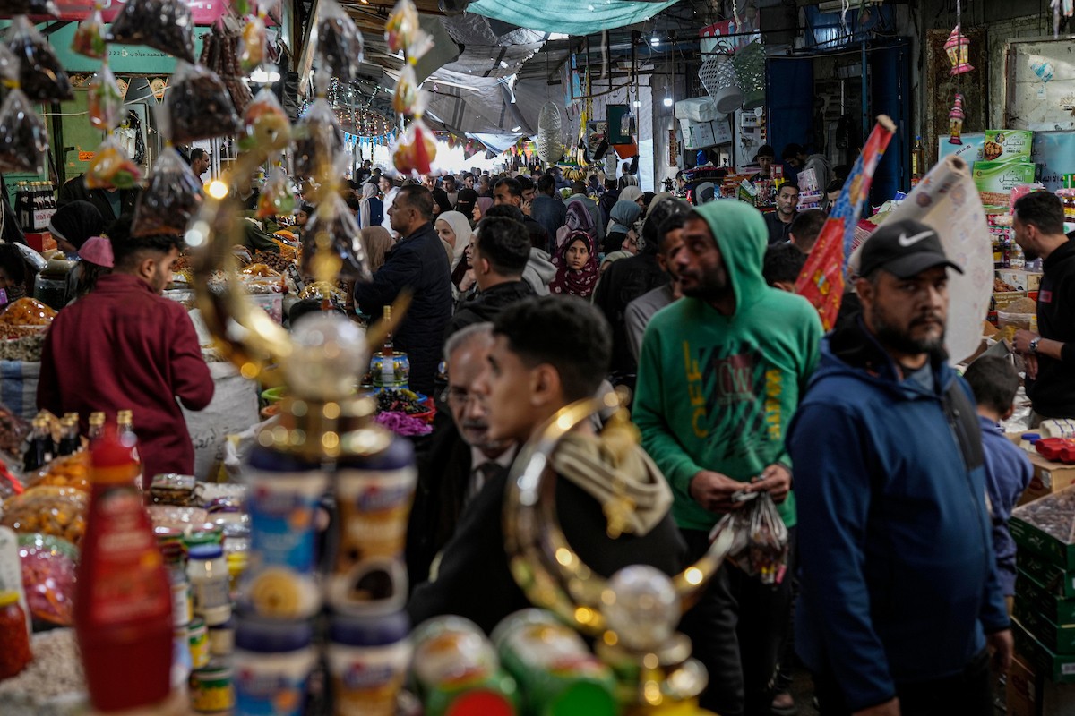 يتسوق الفلسطينيون في أول ليلة من شهر رمضان المبارك في سوق الزاوية، الواقع في قلب مدينة غزة والذي تضرر بشدة جراء الحرب الإسرائيلية. يعرض الباعة بضائعهم على أكشاك مزينة بالفوانيس والأضواء وأطعمة رمضان. مدينة غزة، 17 فبراير/شباط 2026. تصوير: عمر أشتوي