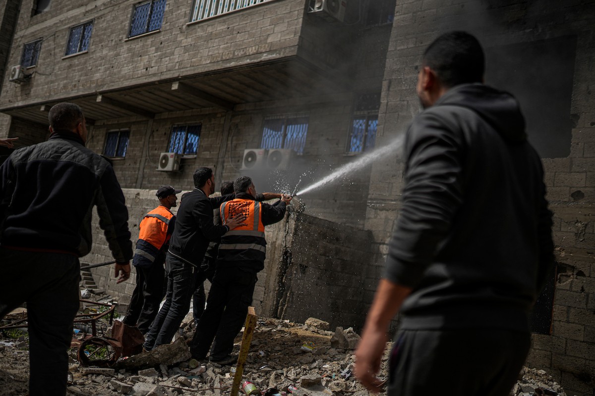 طواقم الدفاع المدني ومتطوعون من المواطنين أثناء محاولة إخماد حريق اندلع في مستودع تابع لمنظمة إغاثة في حي الرمال، غرب مدينة غزة، في 13 فبراير/شباط 2026. صورة: عمر أشتوي